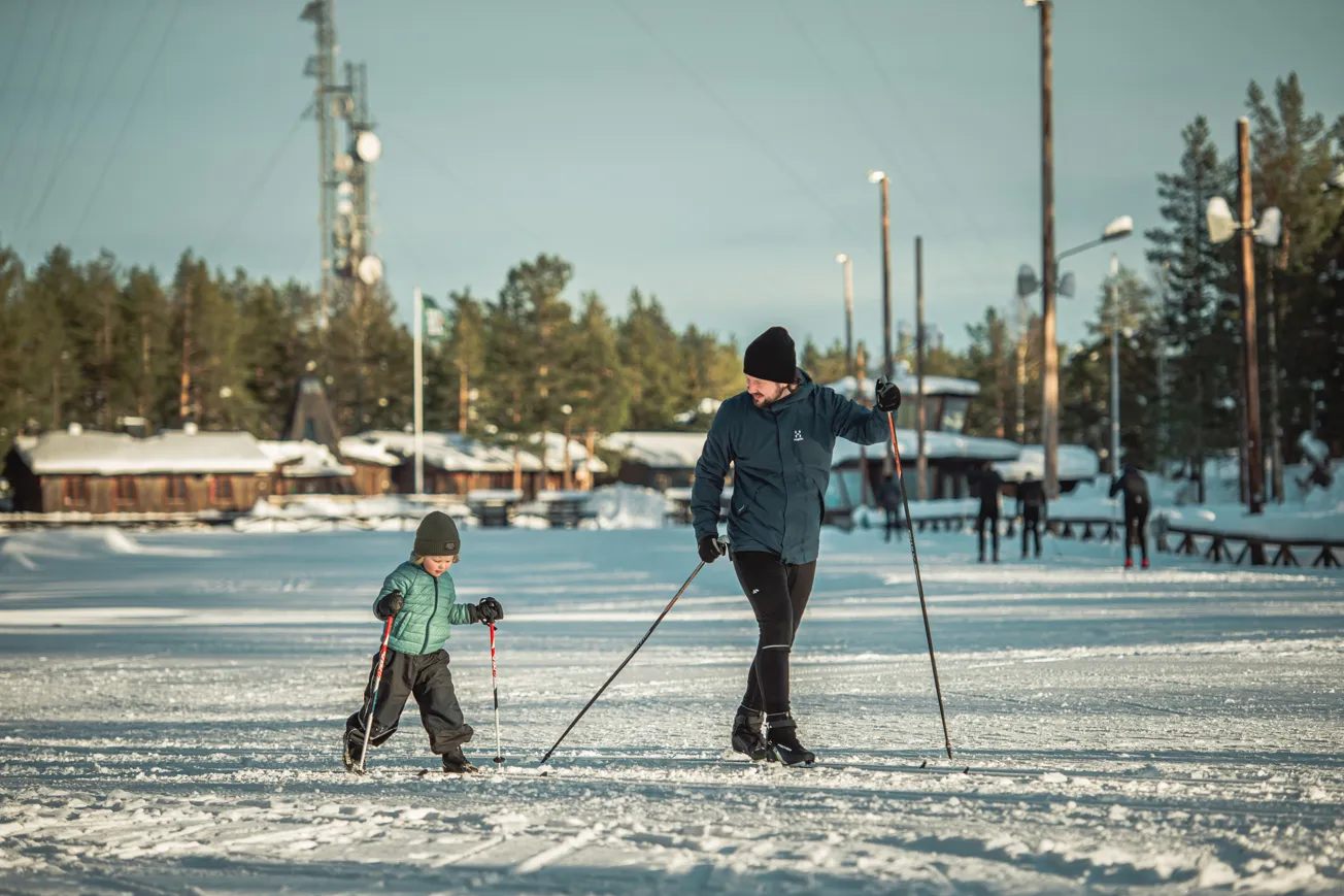 En man och ett barn på skidor i snön.