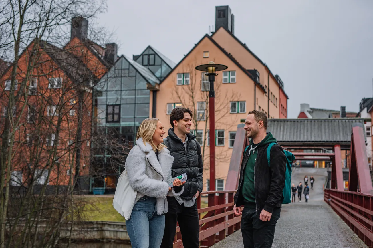 Tre personer står vid en bro utanför Mittuniversitetet.