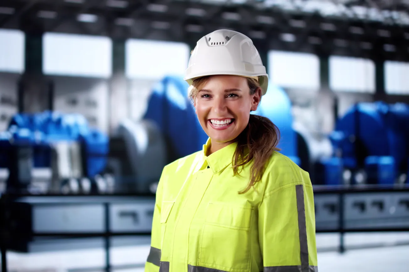 En kvinna med skyddshjälm i en fabrik.