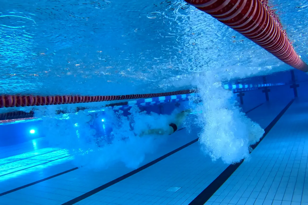En person som simmar i en pool med ett stort rör.