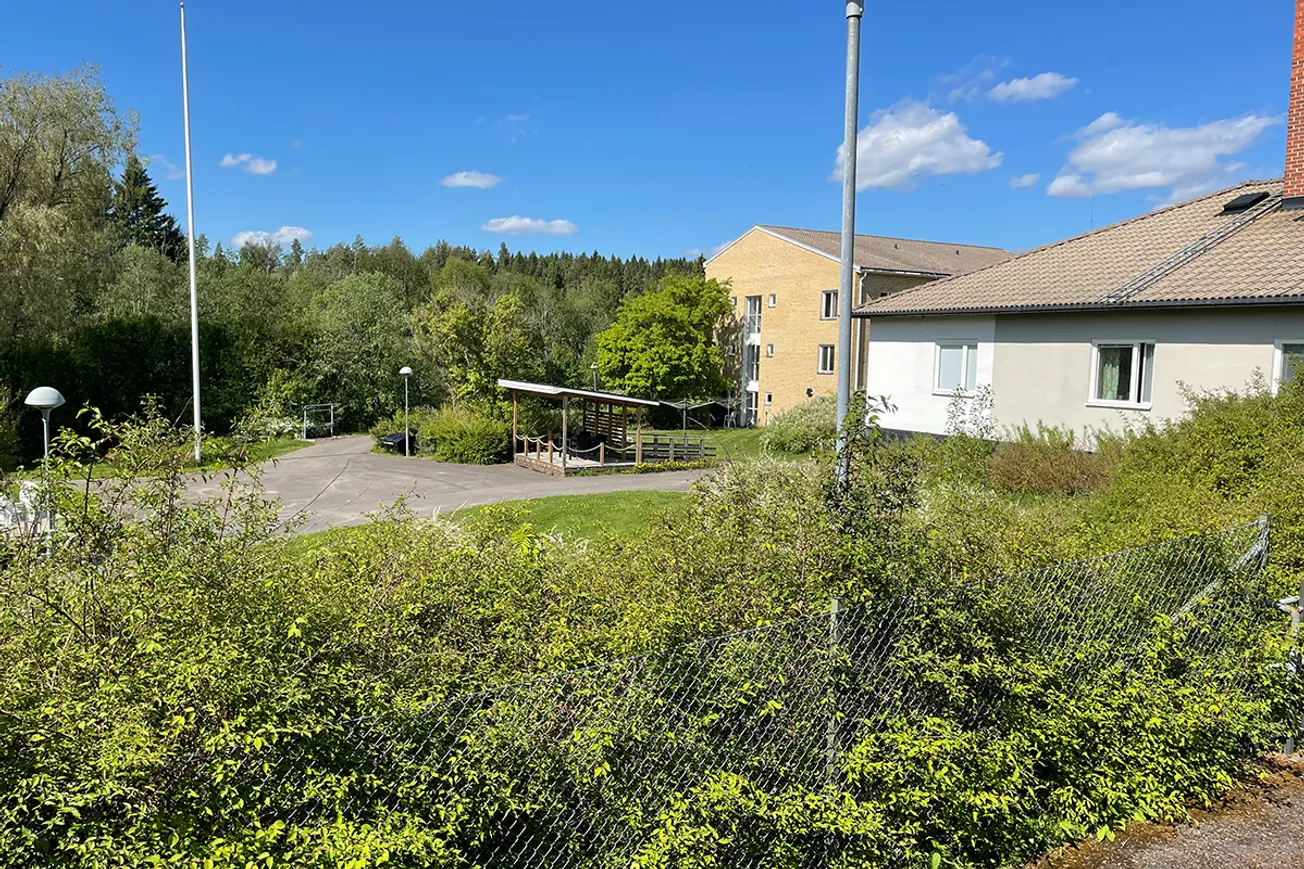 En byggnad omgiven av buskar och träd.
