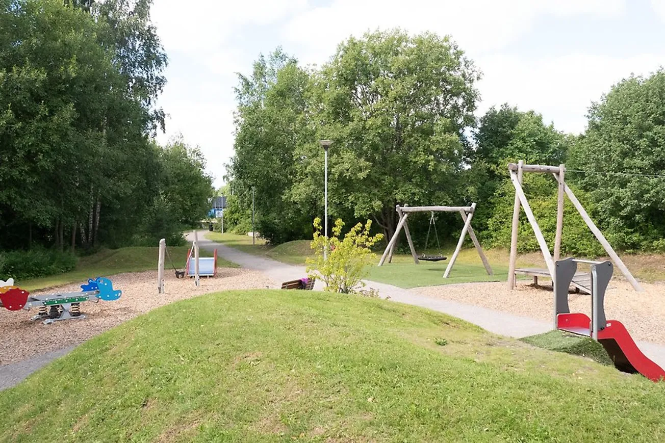 Ortviksparken sommartid med en gungställning och en lekplats.