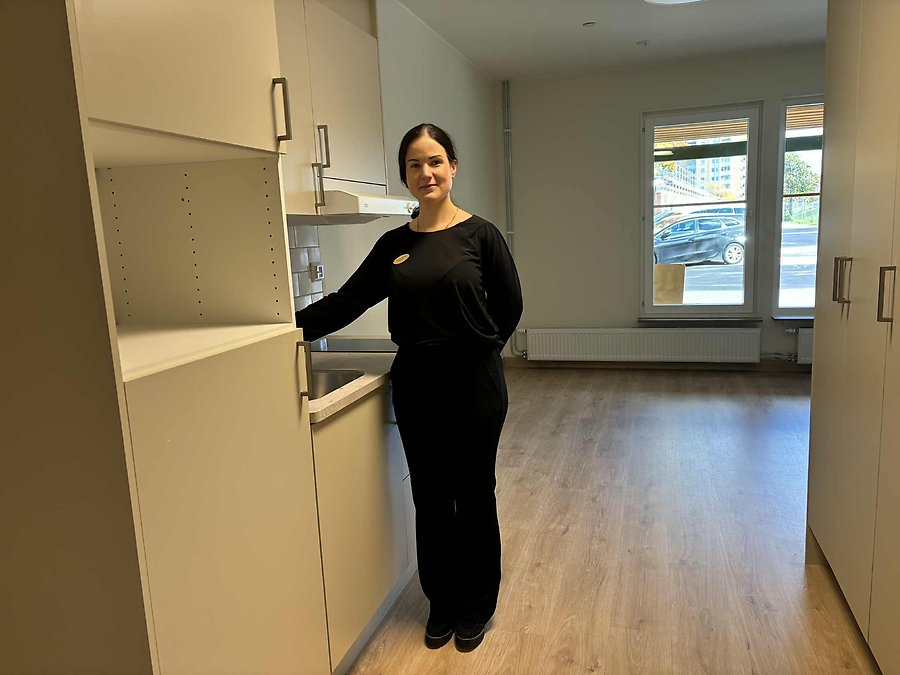 Enhetschef Lina Andersen står bredvid ett kök i en lägenhet på ett äldreboende.