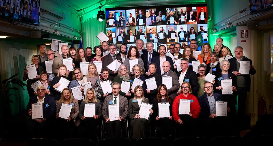 Foto på 48 personer som håller upp påskrivna Klimatkontrakt i en studiomiljö