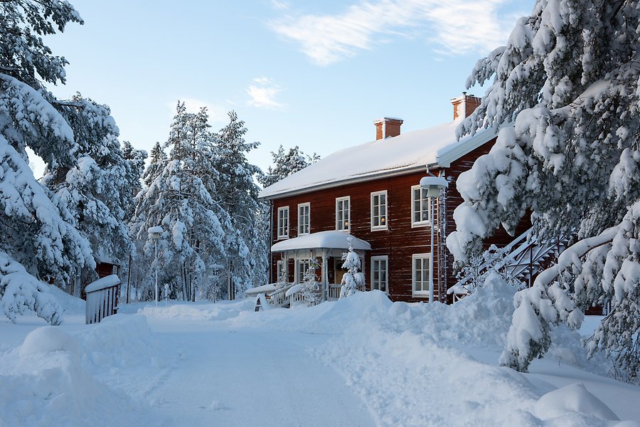 Ett hus i skogen täckt av snö.