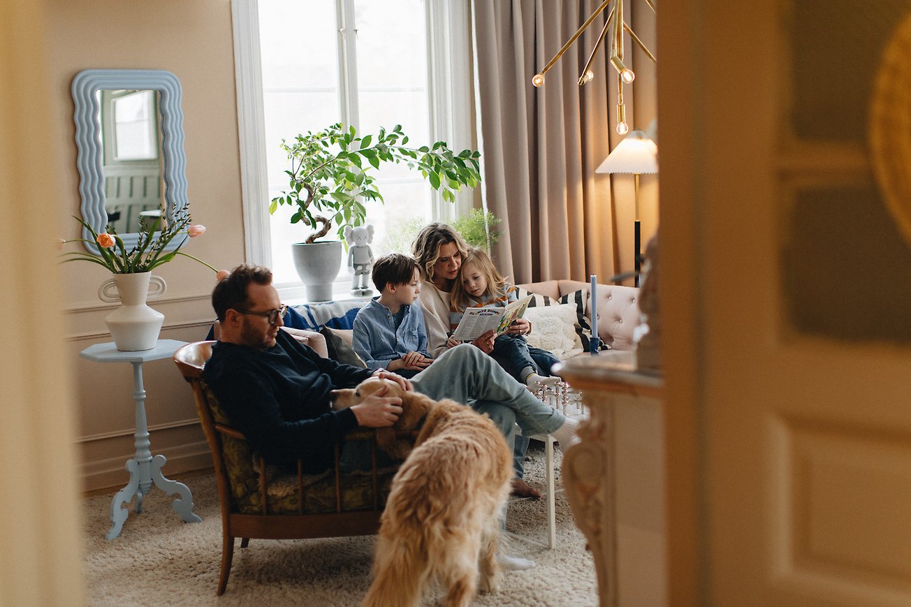 Familj sitter tillsammans i en soffa och läser bok