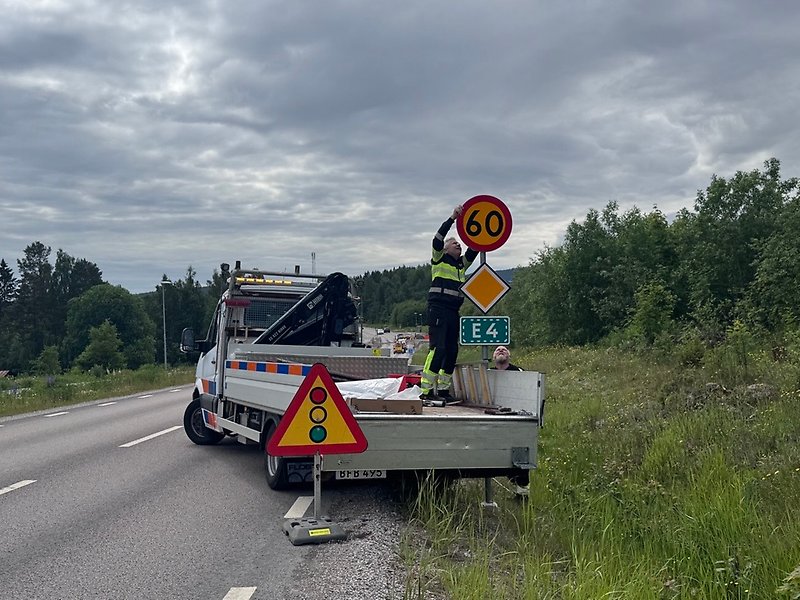 Två män sätter upp en ny vägskylt.
